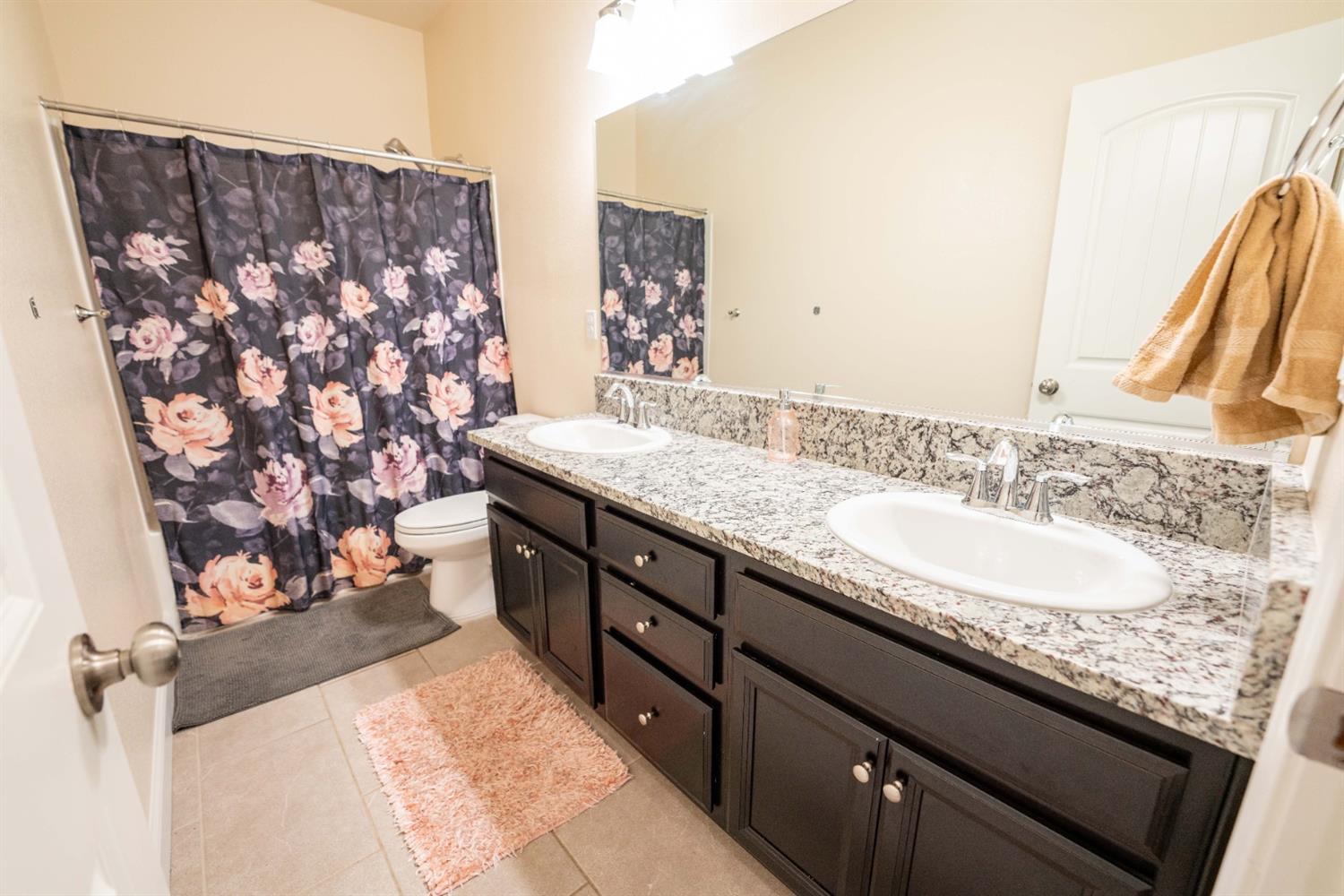 1818 Softwind Drive Tulare, CA 93274 - Photo 26 of 46 a bathroom with a granite countertop sink a mirror and shower