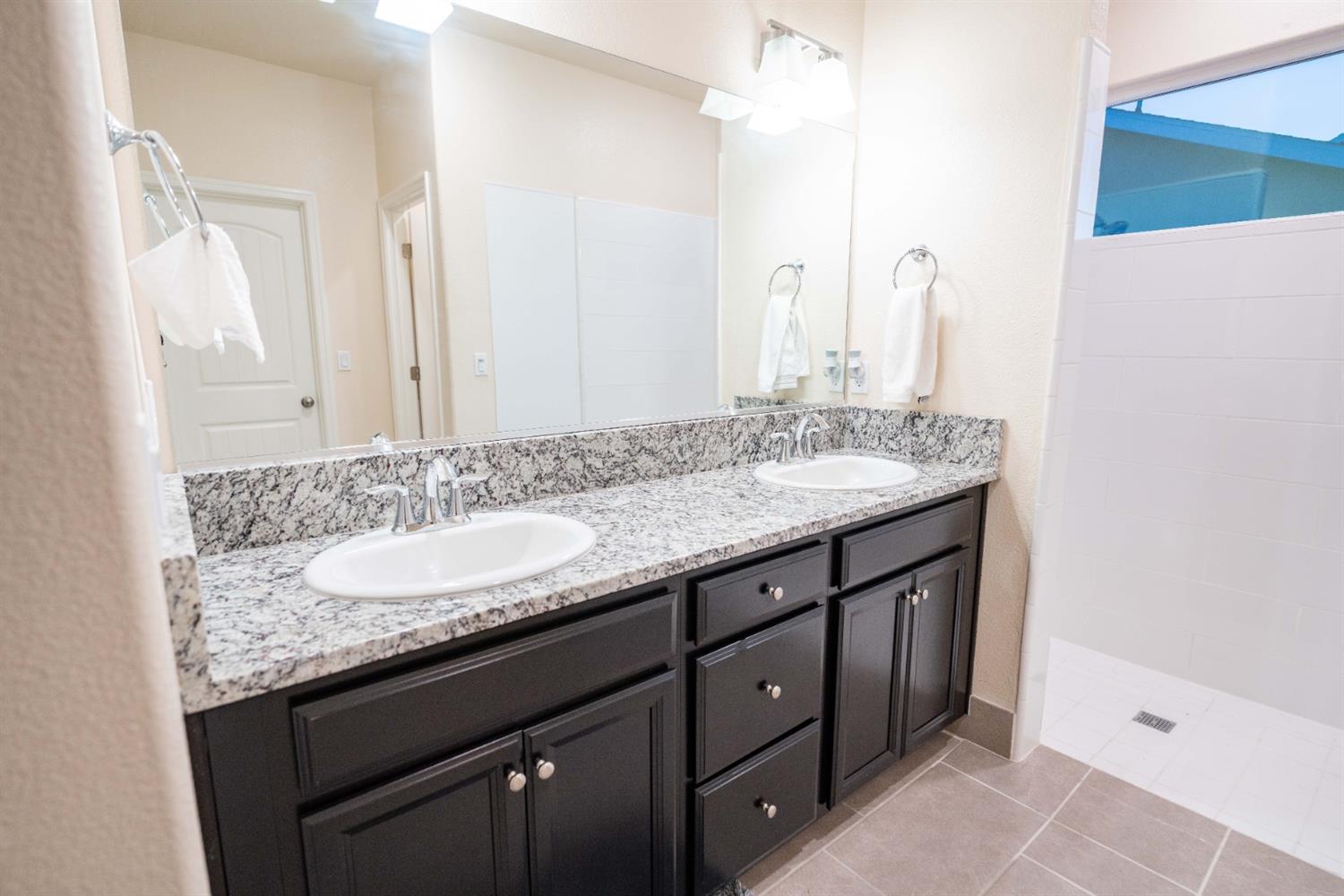 1818 Softwind Drive Tulare, CA 93274 - Photo 31 of 46 a bathroom with a granite countertop sink and a mirror