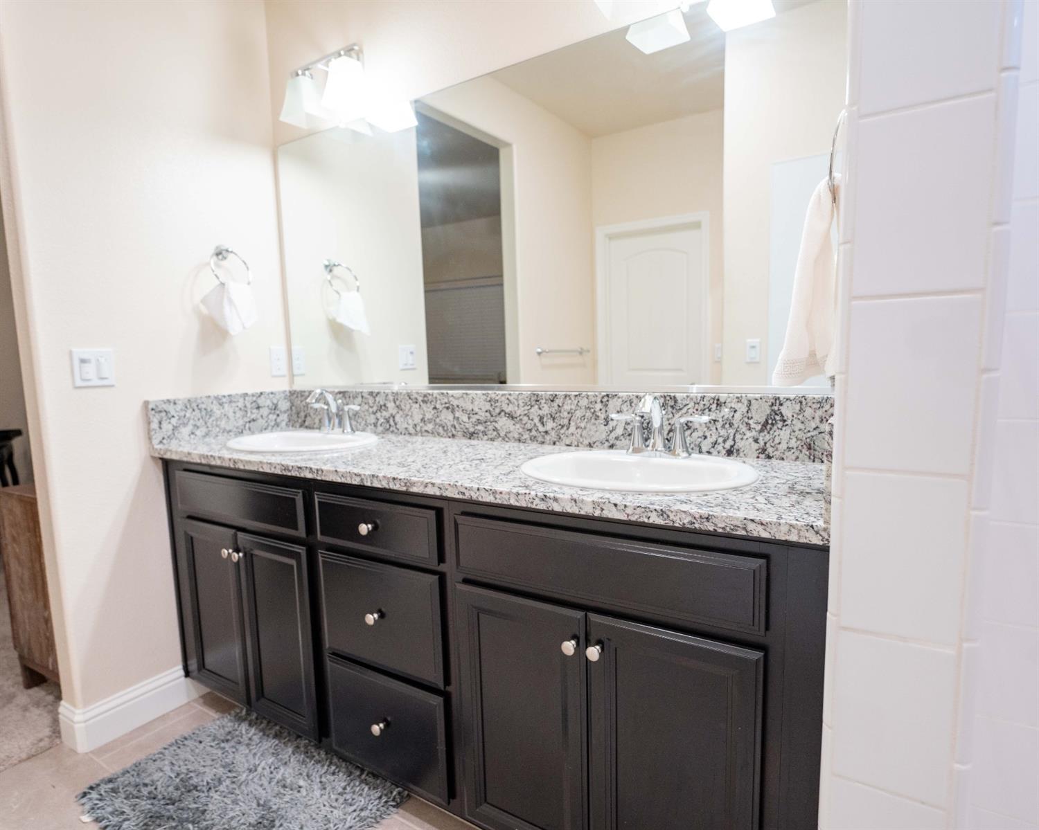 1818 Softwind Drive Tulare, CA 93274 - Photo 33 of 46 a bathroom with a granite countertop sink and a mirror