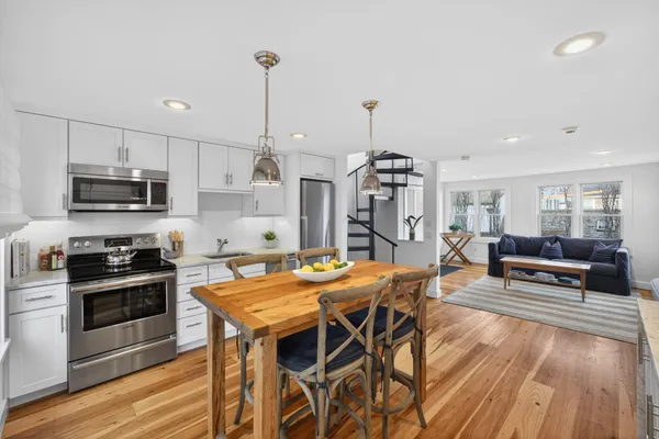 a view of a kitchen with granite countertop kitchen island stainless steel appliances a stove a sink a dining table and chairs