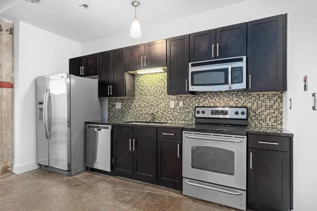 a kitchen with granite countertop stainless steel appliances and refrigerator