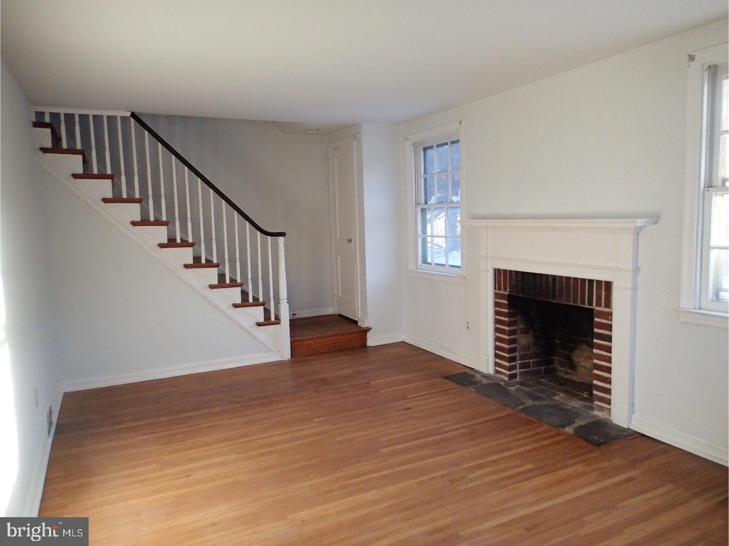 249 Fairview Road Springfield, PA 19064 - Photo 2 of 16 a view of an empty room with wooden floor fireplace and a window