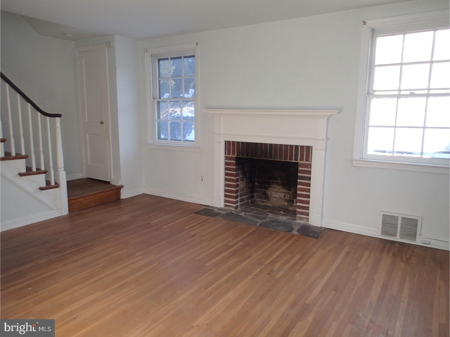 249 Fairview Road Springfield, PA 19064 - Photo 4 of 16 a view of an empty room with wooden floor fireplace and a window