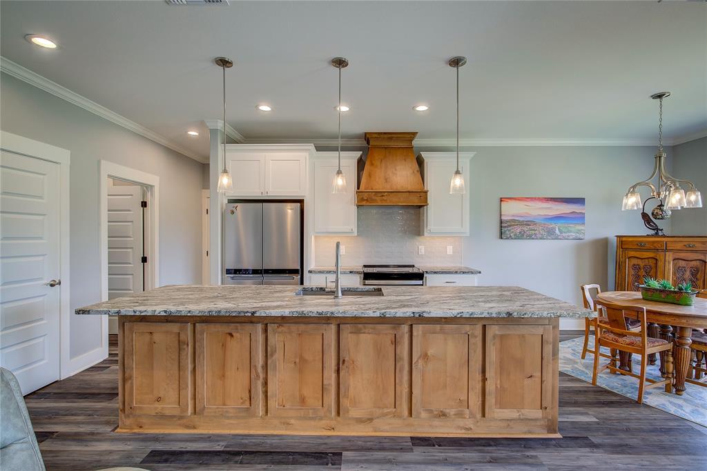 326 Koby Circle Sulphur Springs, TX 75482 - Photo 9 of 38 Kitchen has an island with a long breakfast bar and pendant lights, custom wood cabinets, and a leathered quartz countertop for durability!