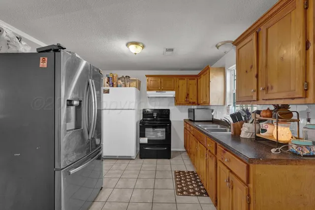 a kitchen with granite countertop a refrigerator and a stove top oven