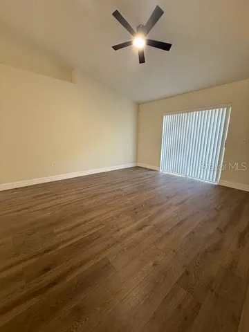 an empty room with wooden floor fan and windows