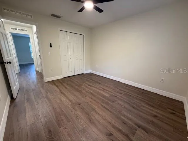 an empty room with wooden floor and a ceiling fan