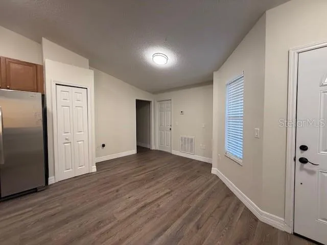 a view of an empty room with wooden floor and a closet