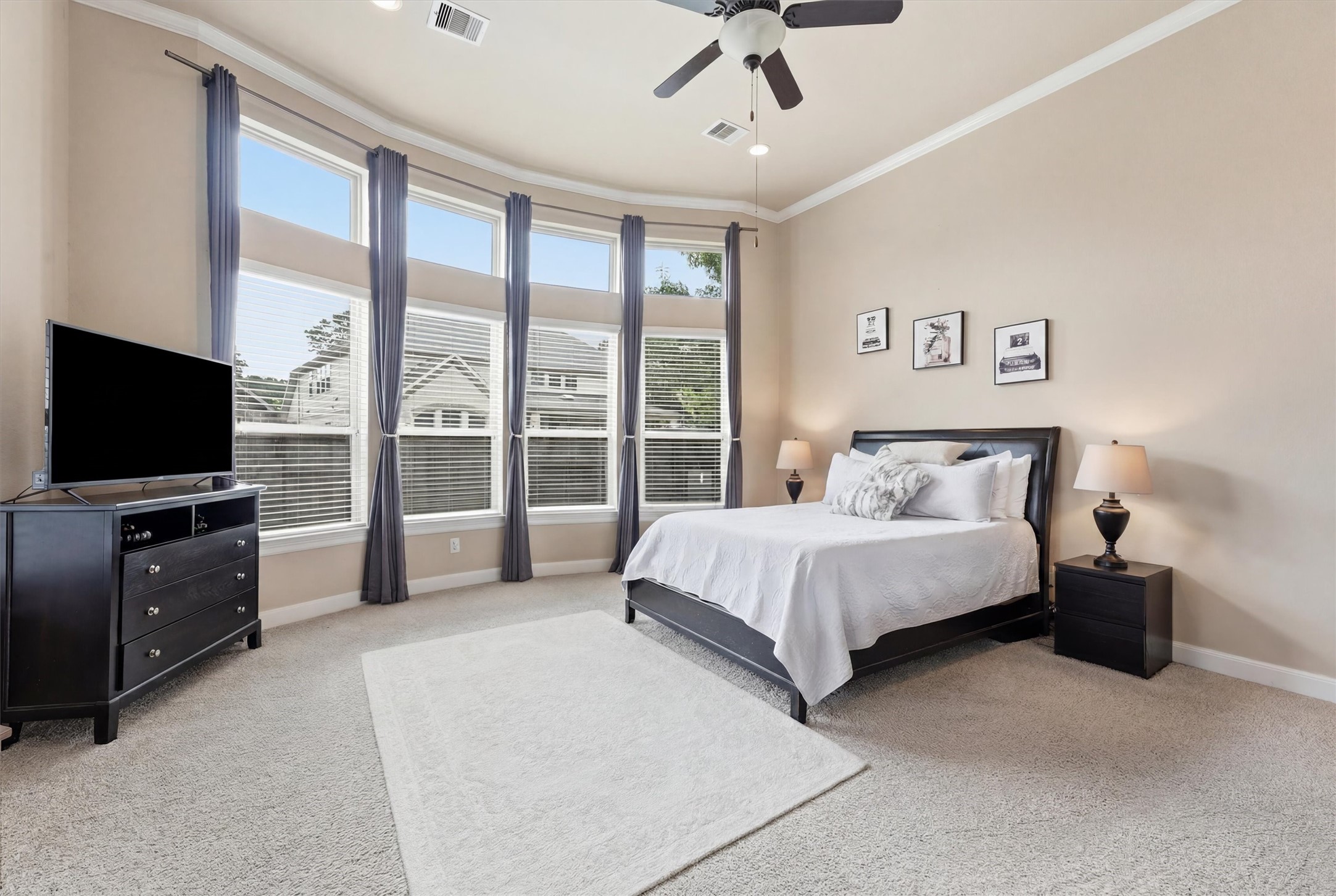 17710 Rough River Court Humble, TX 77346 - Photo 15 of 38 This spacious primary bedroom features large bay windows with ample natural light, a neutral color scheme, and elegant furnishings, including a cozy bed and modern dresser.