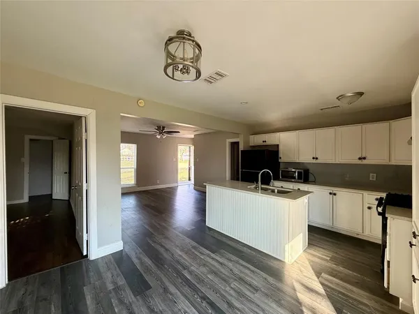 a kitchen with a counter top space a sink wooden floor and a large window