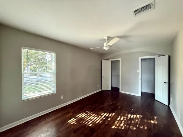 a view of an empty room with window and wooden floor