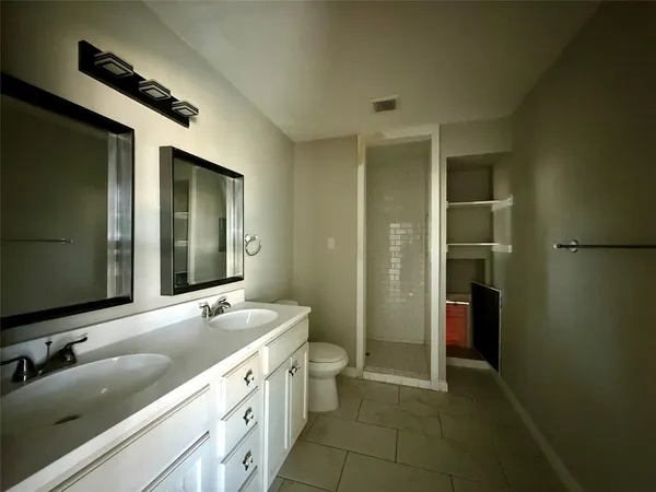 a spacious bathroom with a double vanity sink a large mirror and a shower