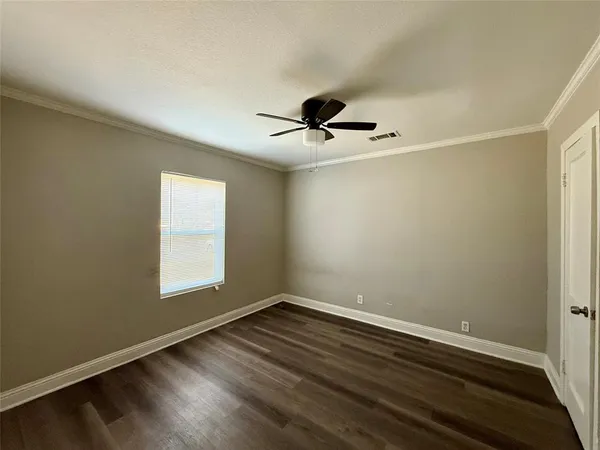 a view of empty room with wooden floor and fan