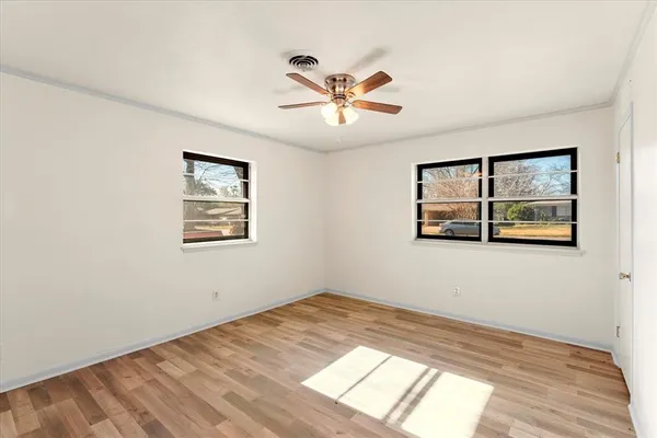 a view of empty room with wooden floor and fan