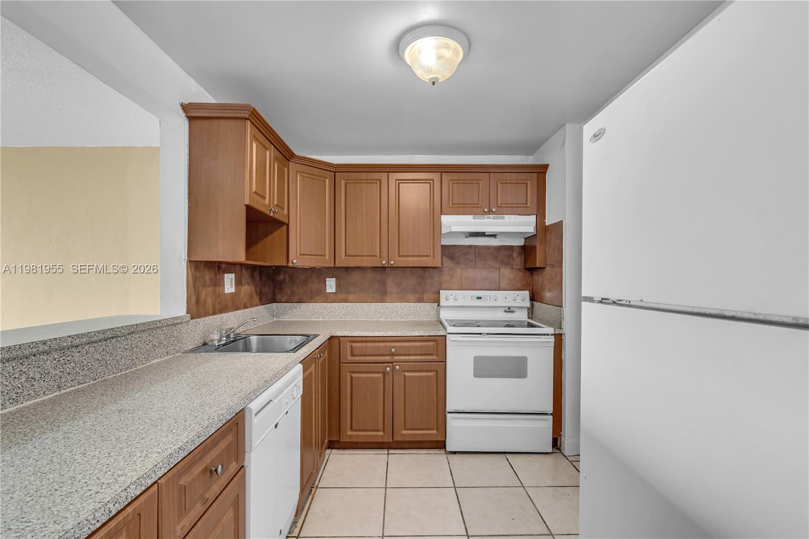 9143 Southwest 77th Avenue, Unit B802 Miami, FL 33156 - Photo 5 of 33 a kitchen with a stove a sink and a refrigerator