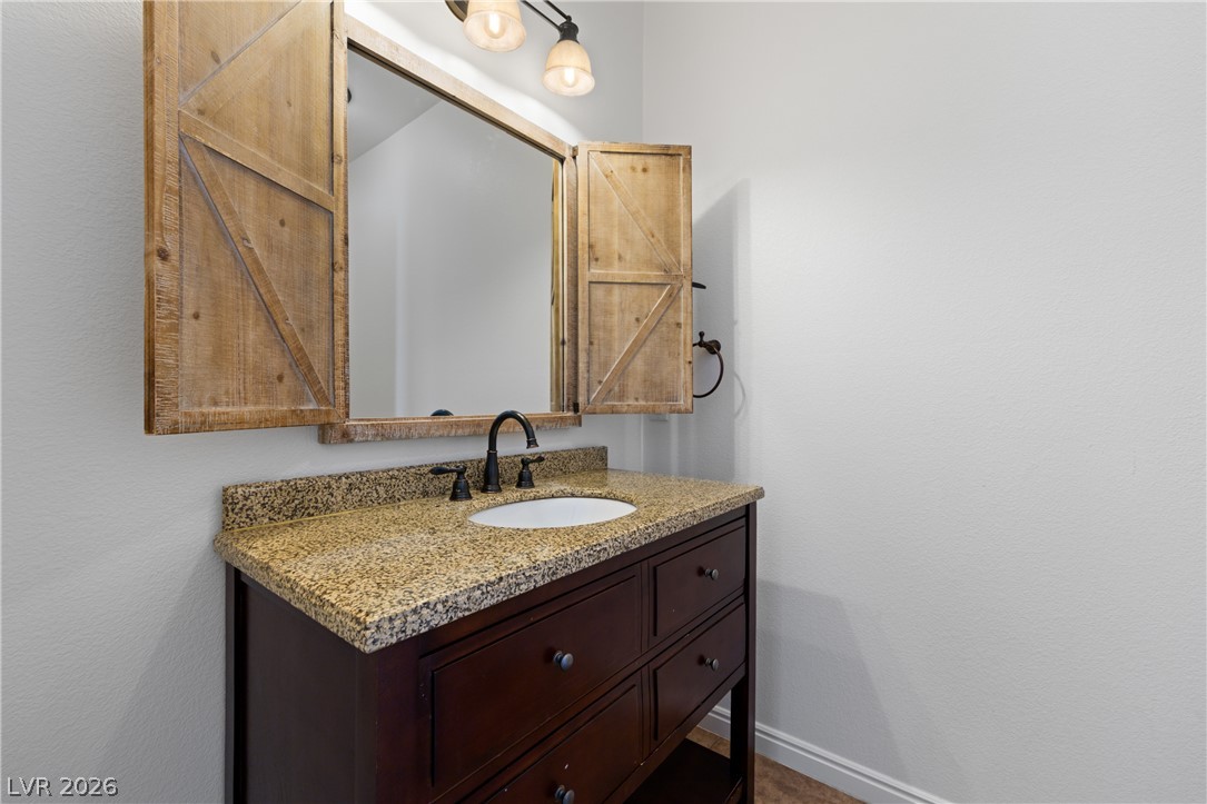 575 Gann Avenue Logandale, NV 89021 - Photo 9 of 75 A well-appointed vanity with a granite countertop and rustic mirror offers convenient storage and farmhouse charm.