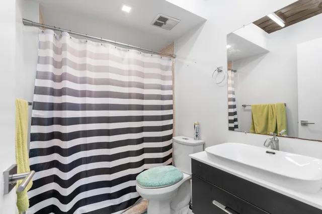 a bathroom with a sink a toilet a mirror and shower curtain