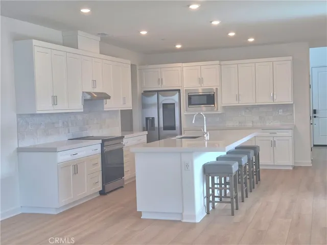 a kitchen with stainless steel appliances granite countertop a white cabinets and wooden floor