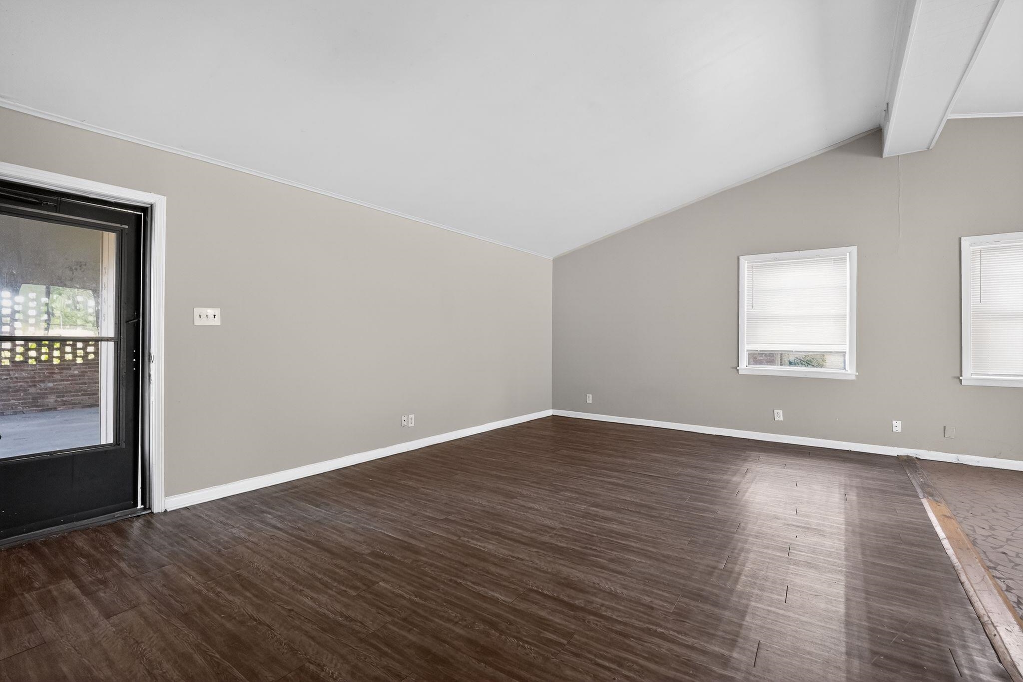 3445 Powers Road Memphis, TN 38128 - Photo 14 of 35 Spacious room featuring vaulted ceilings with exposed beams, wood-finish flooring, two windows with blinds, and a glass-paneled exterior door