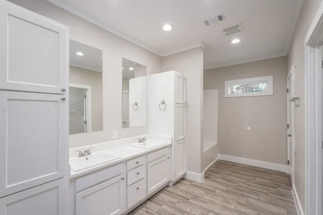 a spacious bathroom with a double vanity sink a large mirror and shower