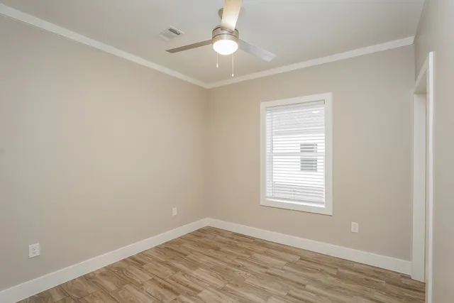 an empty room with wooden floor ceiling fan and windows