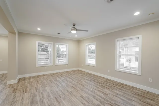 a view of an empty room with a window and wooden floor