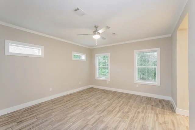 a view of an empty room with wooden floor and a window