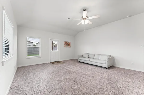 an empty room with chandelier fan and windows