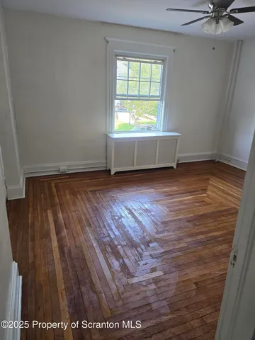 a view of an empty room with a window and wooden floor