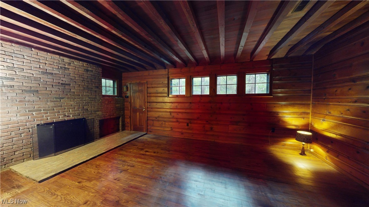 13696 Sperry Road Novelty, OH 44072 - Photo 20 of 40 Unfurnished room with wood walls, a brick fireplace, brick wall, and hardwood / wood-style floors