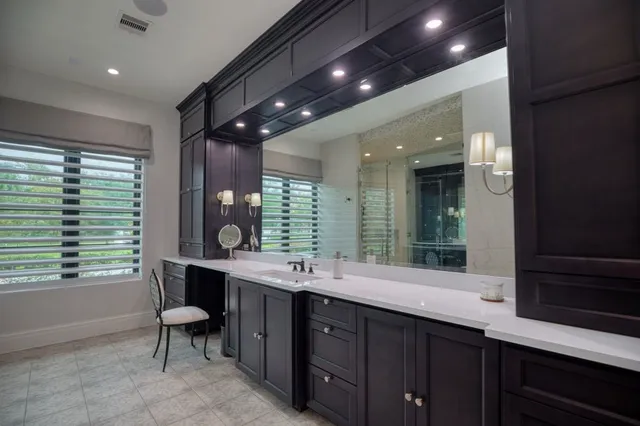 a bathroom with a double vanity sink a large mirror and a bathtub