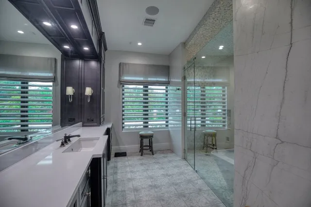 a bathroom with a sink a large mirror and a glass door shower