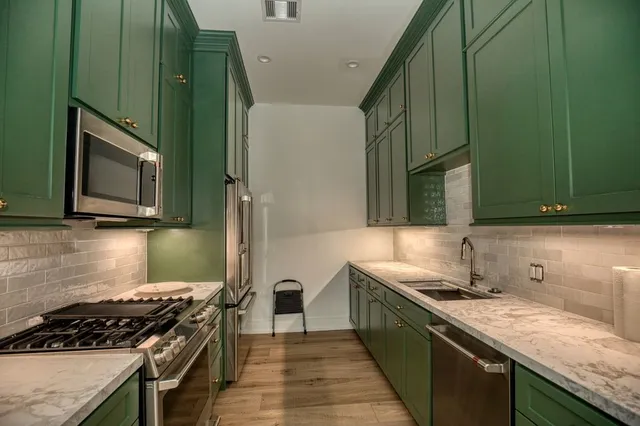 a kitchen with stainless steel appliances granite countertop a sink and a stove top oven