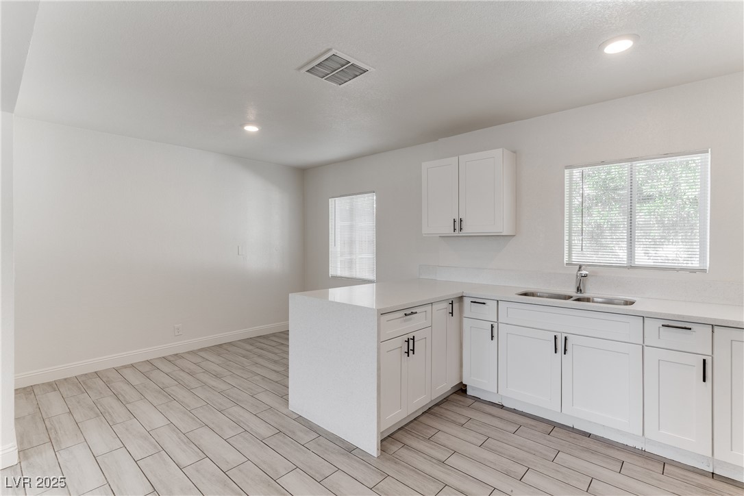 309 North 16th Street, Unit A Las Vegas, NV 89101 - Photo 11 of 23 Kitchen with light stone counters, a peninsula, wood tiled floors, white cabinets, and recessed lighting