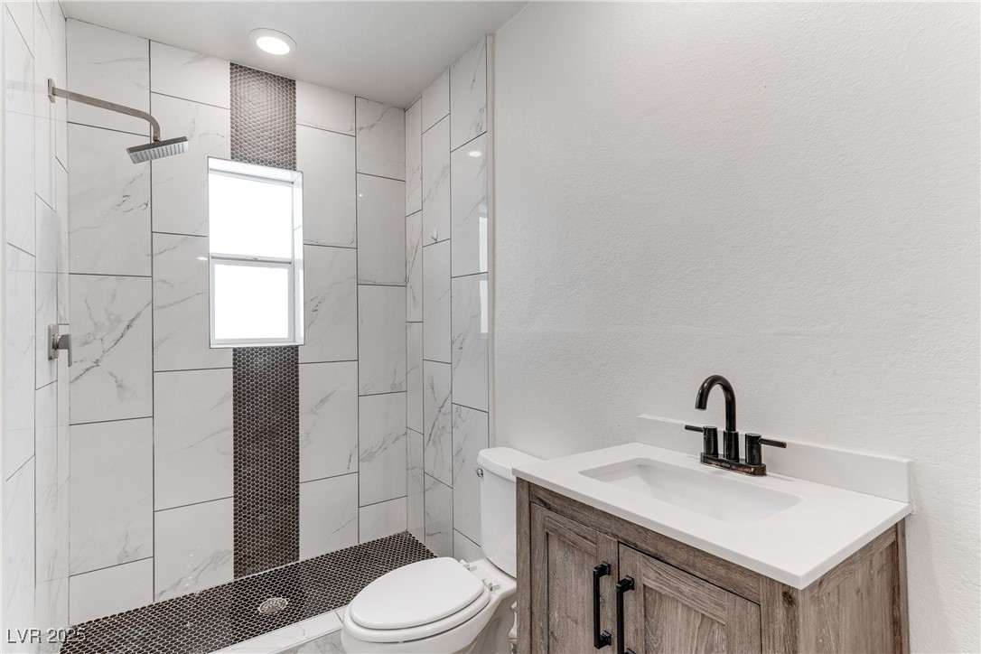 309 North 16th Street, Unit A Las Vegas, NV 89101 - Photo 17 of 23 Full bath featuring a textured wall, a stall shower, and vanity