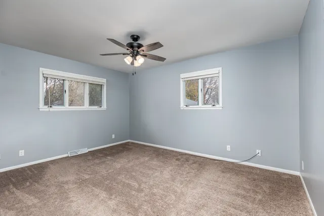 an empty room with windows and fan