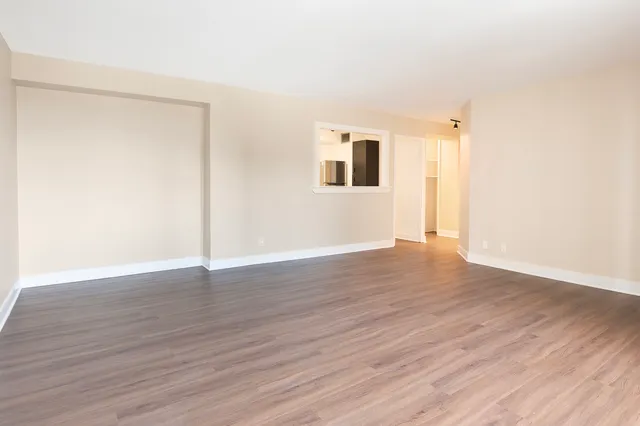 a view of an empty room with wooden floor