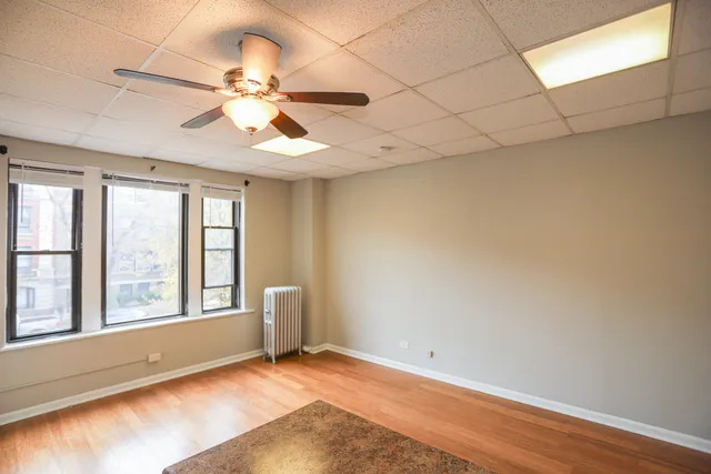 an empty room with windows and fan