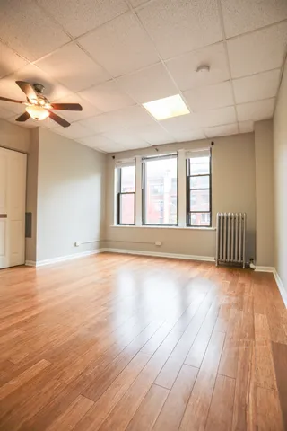 a view of an empty room with window and wooden floor
