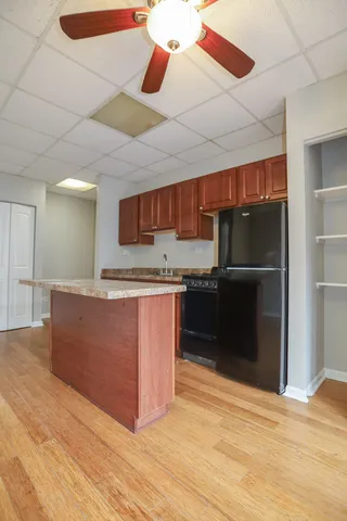 a kitchen with stainless steel appliances granite countertop a refrigerator and a wooden floors
