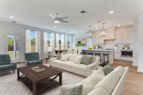 a living room with furniture kitchen view and a large window