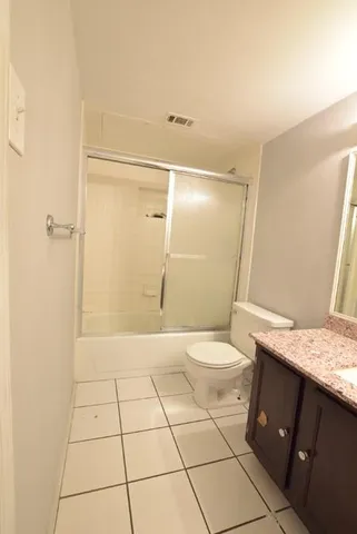 a bathroom with a granite countertop sink a toilet and a shower