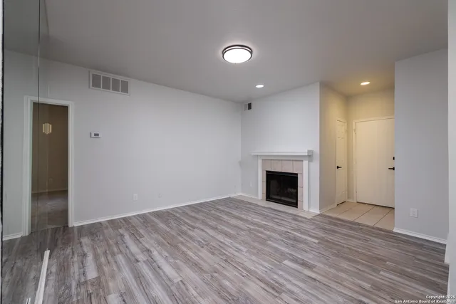 an empty room with wooden floor and fireplace