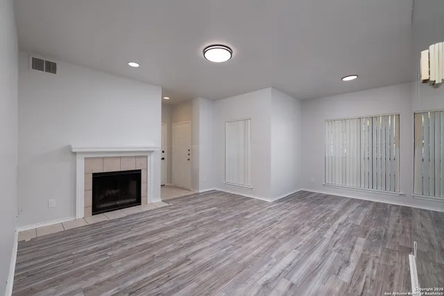 an empty room with wooden floor and fireplace