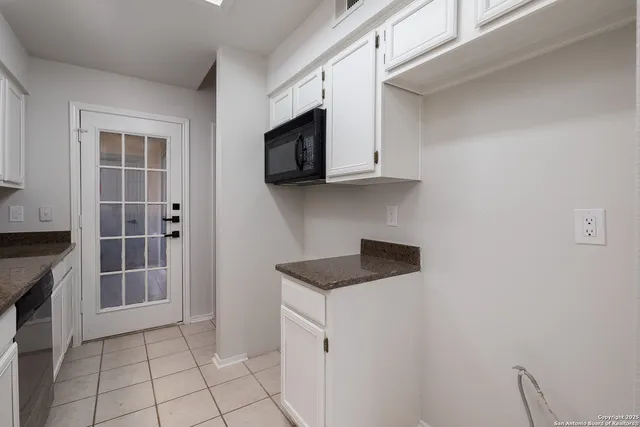 a kitchen with granite countertop a sink a stove and cabinets