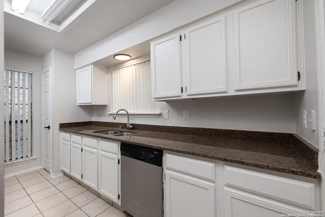 a kitchen with granite countertop white cabinets and a sink