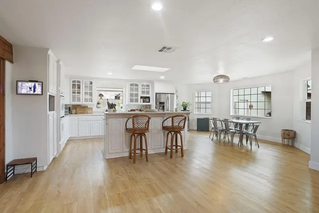 a living room with stainless steel appliances kitchen island a table and chairs in it