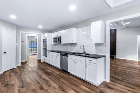 a large kitchen with stainless steel appliances granite countertop a stove and a refrigerator