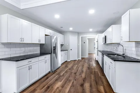 a kitchen with granite countertop a sink a counter space stainless steel appliances and cabinets