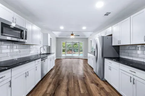 a large kitchen with stainless steel appliances granite countertop a stove a sink dishwasher and a microwave oven with cabinets